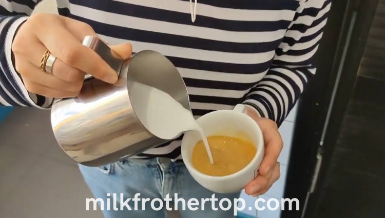 Pouring steamed milk into espresso